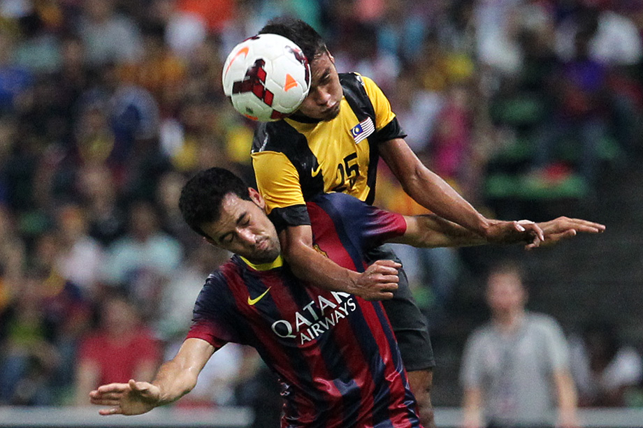 Malaysia's, Wan Zack Haikal ( R ) battles with Barcelona's, Sergio Busquets ( L ) during the friendly match between Malaysia and Barcelona at Stadium Shah Alam, outside Kuala Lumpur. Barcelona's wins the match 3-1. AUGUST 10, 2013. PHOTO SINAR HARIAN/SAFWAN MANSOR